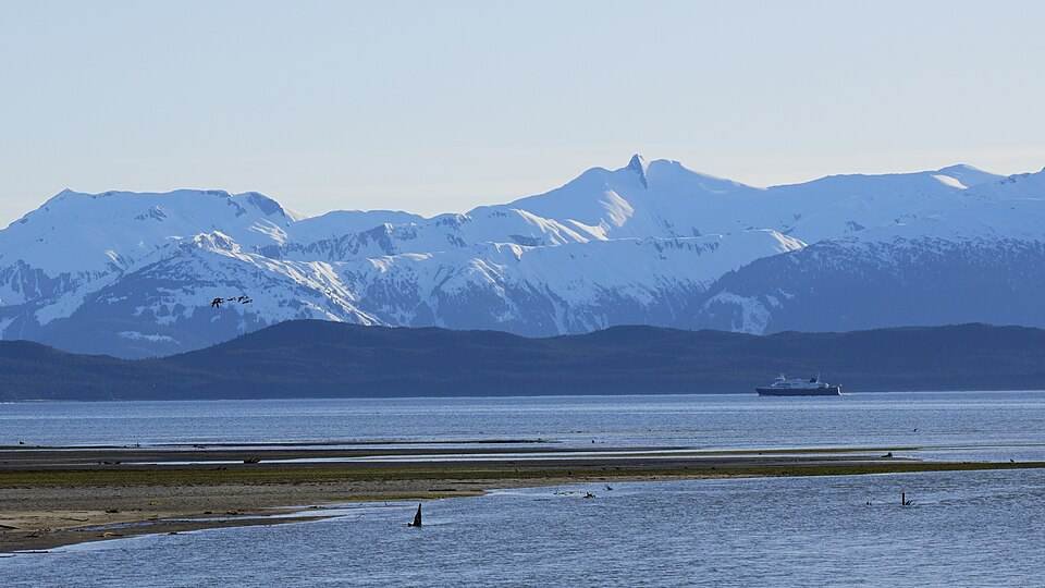 An Alaska Marine Highway ferry sailing past snowy mountains near Juneau