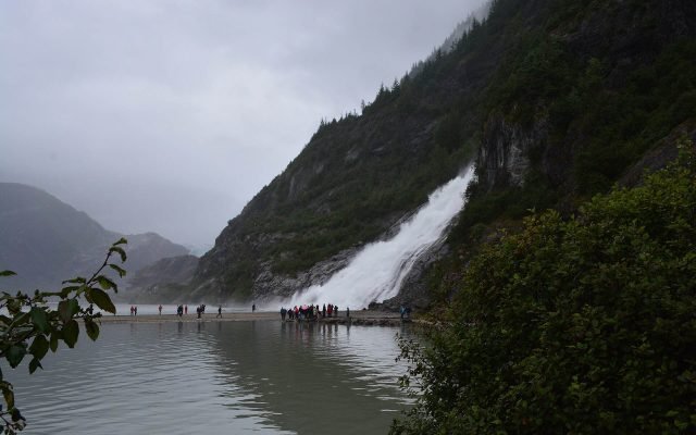 Nugget Falls pouring into Mendenhall Lake below a steep forested mountainside