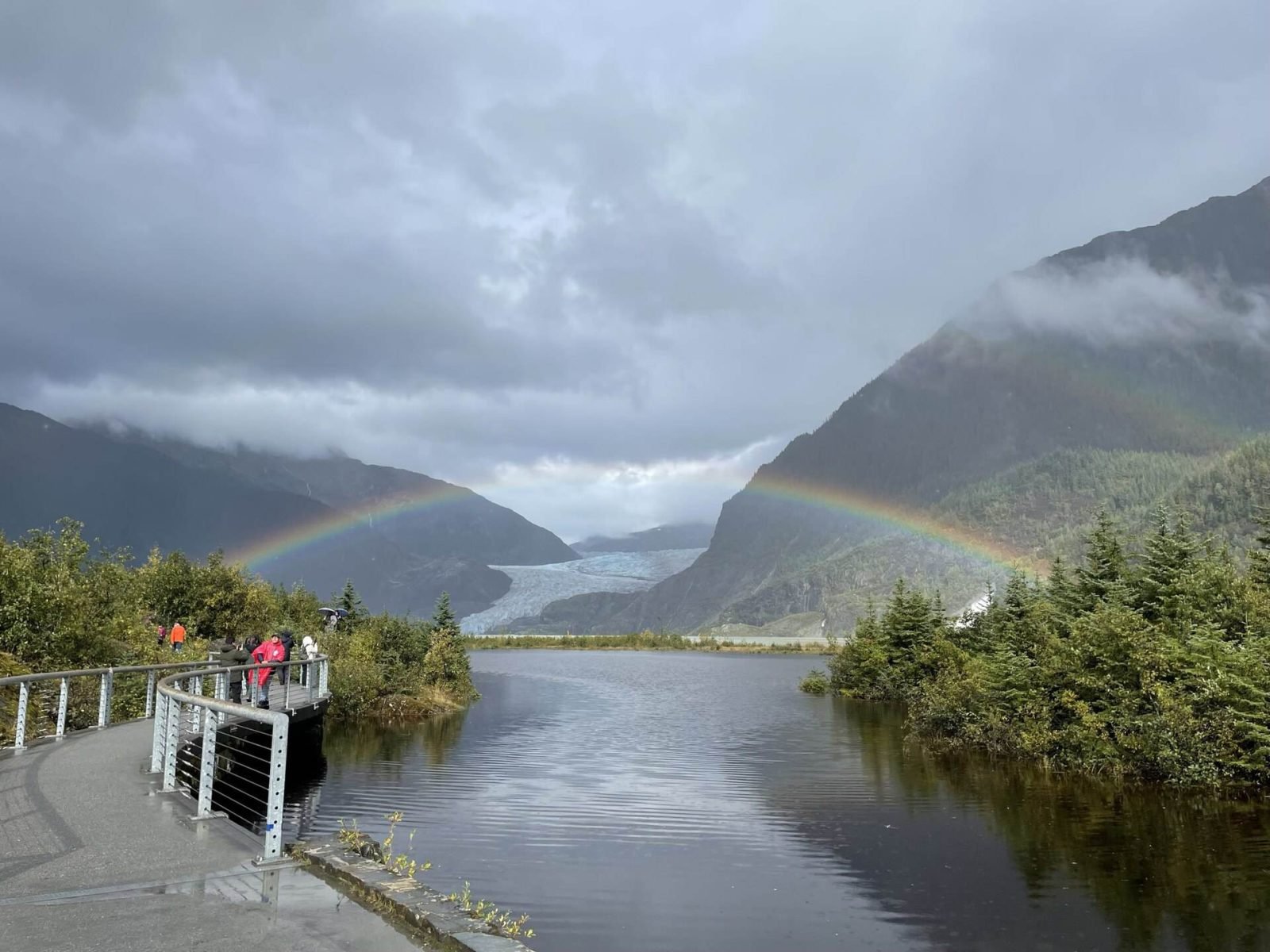 Visitors on the Photo Point walkway as a double rainbow arcs over the glacier and lake