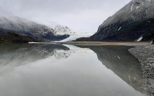 Mendenhall Glacier and snow-dusted mountains reflected in the still lake on a grey winter day